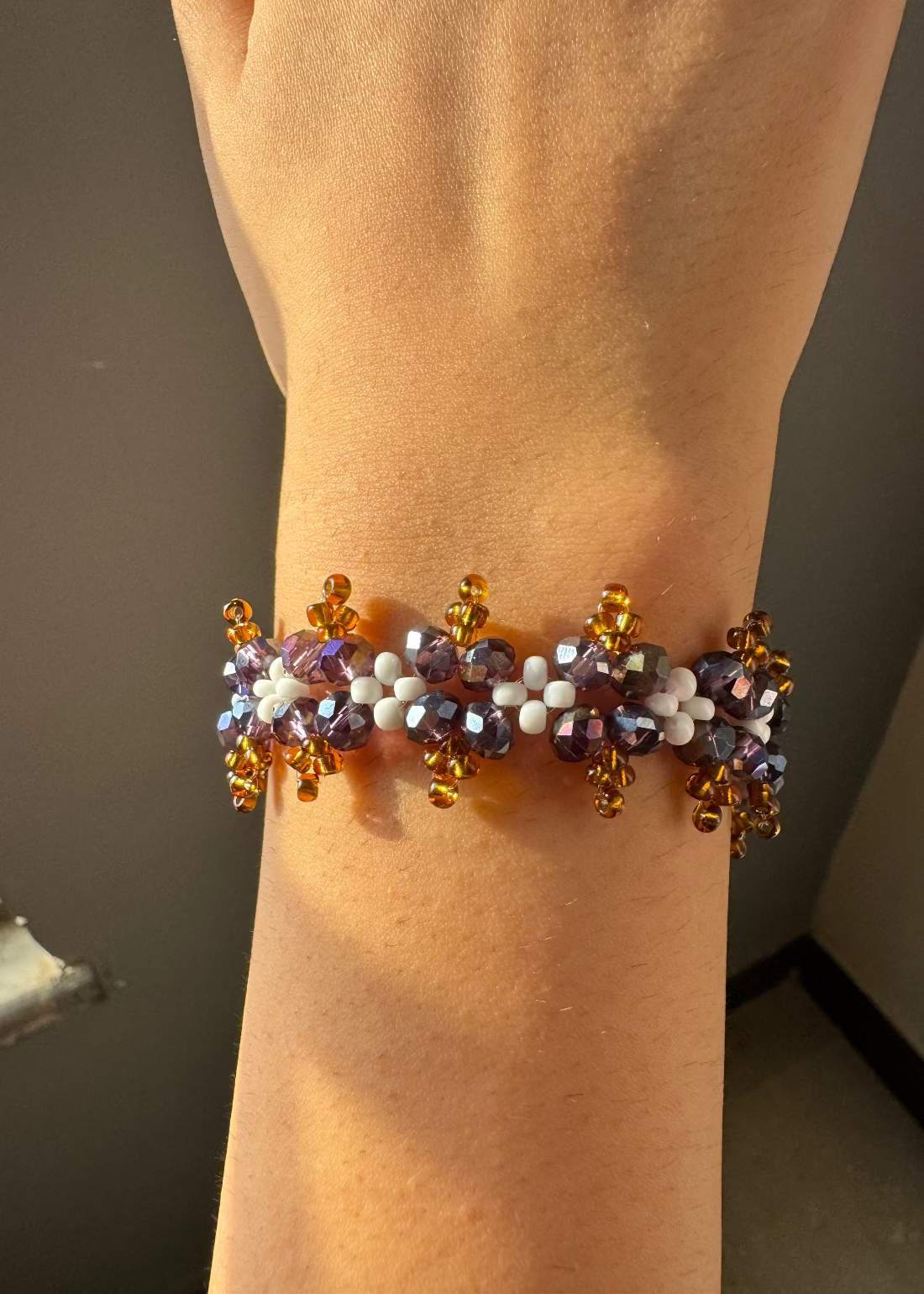 Multicolored beaded bracelet on a wrist against a neutral background