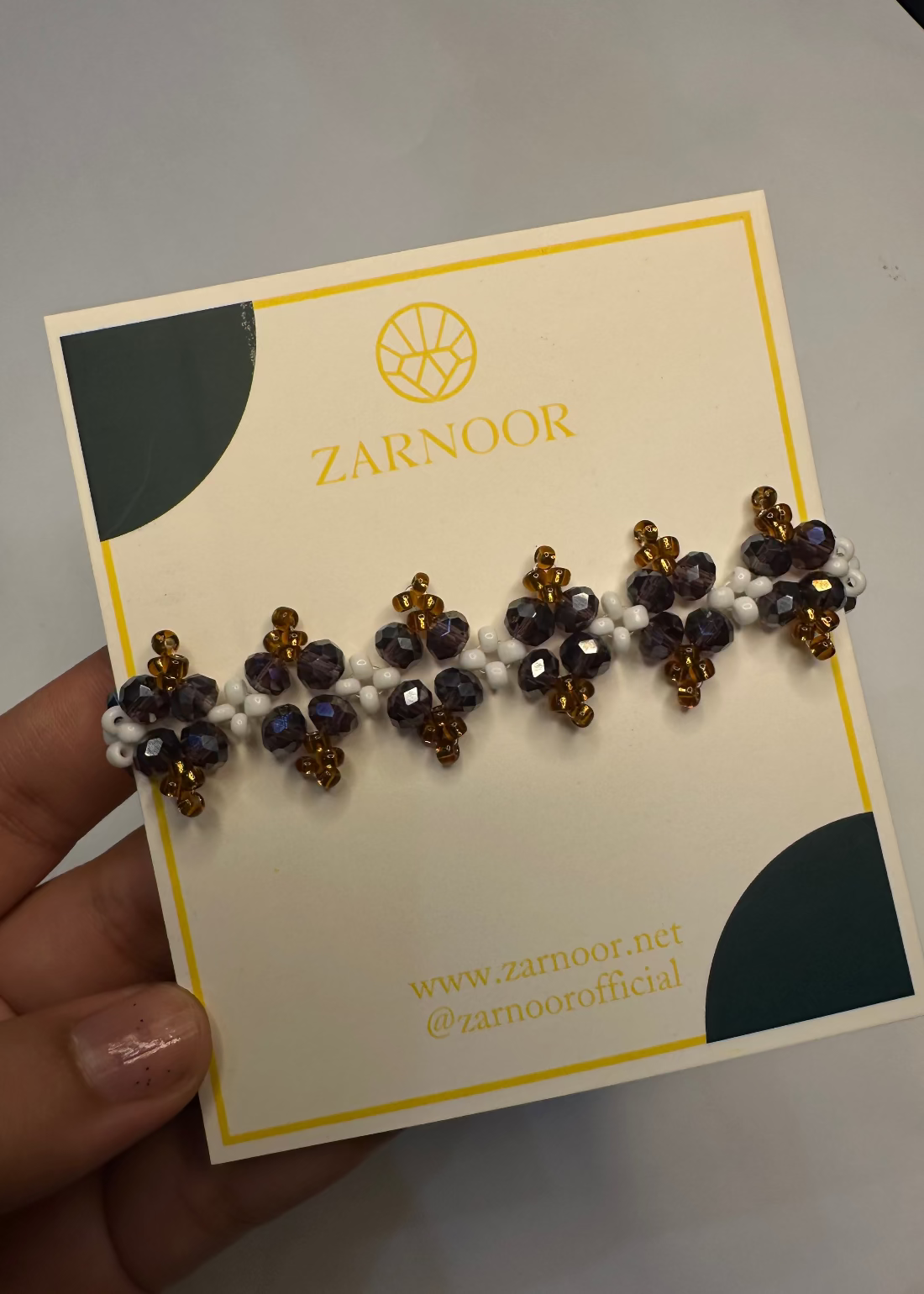 a bracelet on a Zarnoor branded card held by a hand.
