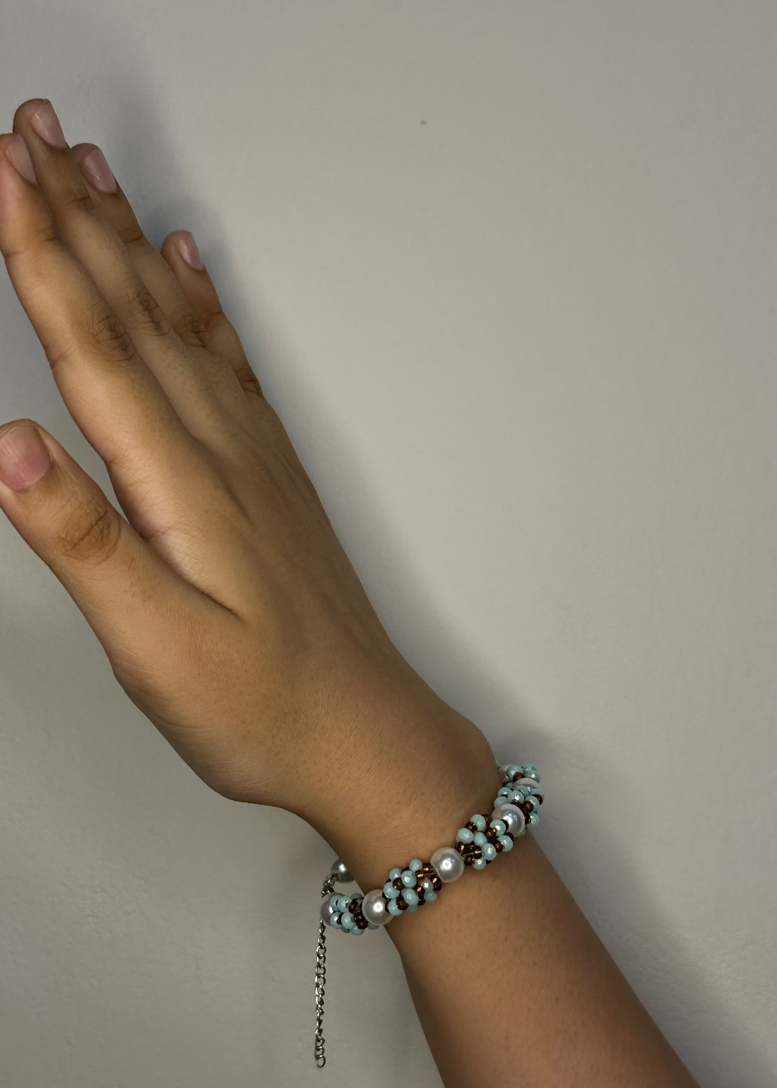 Hand wearing a bracelet on a plain background