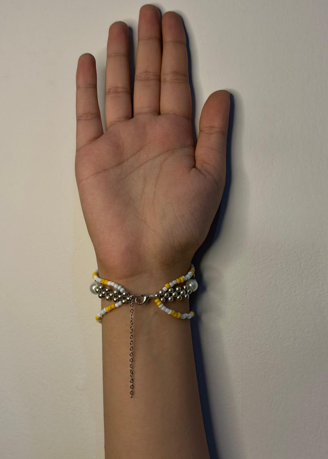 Hand wearing a bracelet on a plain background