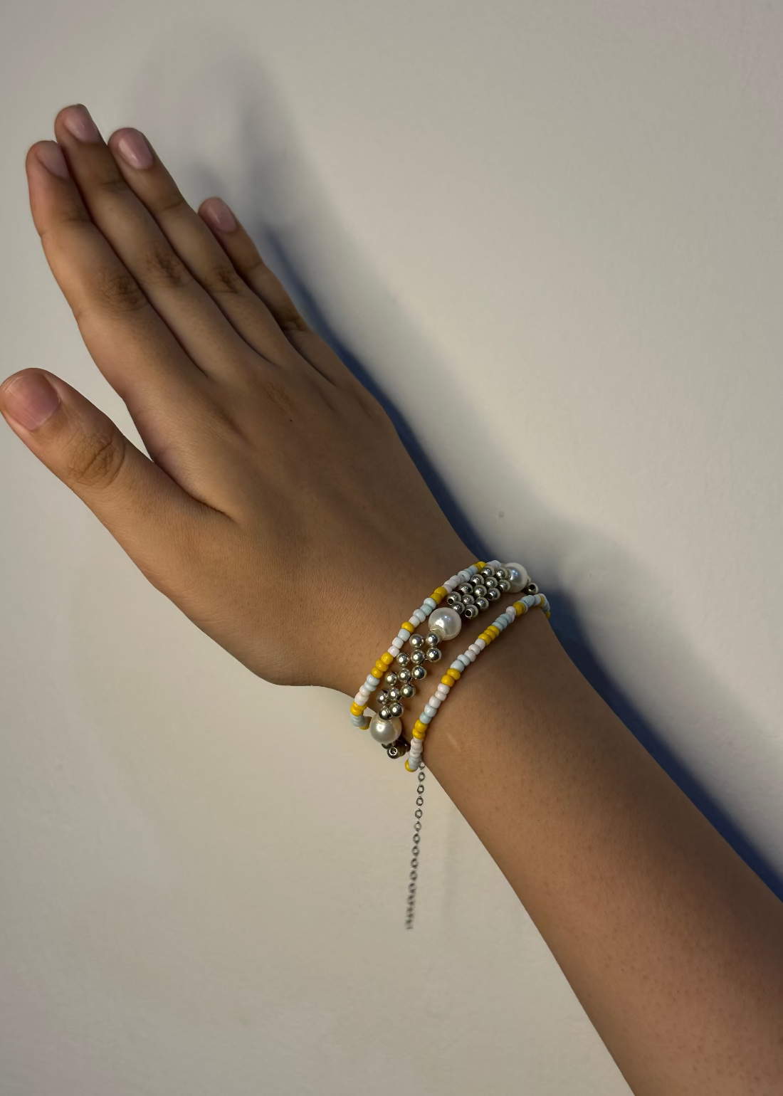 Hand wearing a beaded bracelet on a plain background