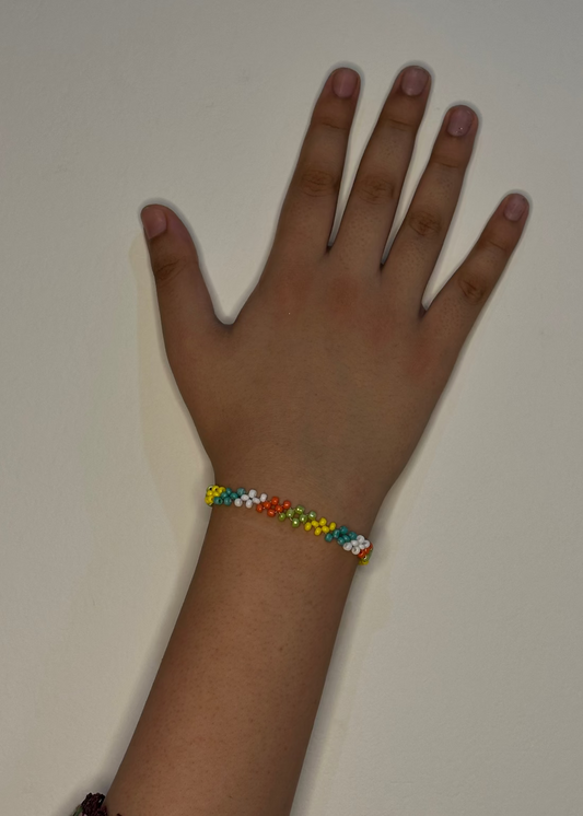 Hand wearing a colorful beaded bracelet on a plain background