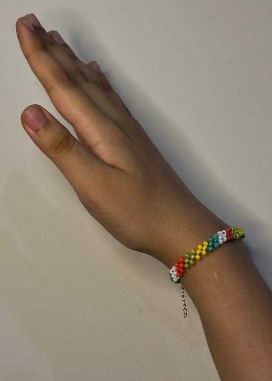 Hand wearing a colorful beaded bracelet on a plain background