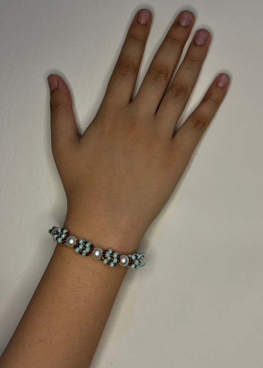 Hand wearing a beaded bracelet on a plain background