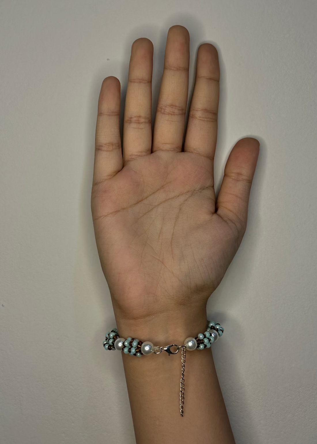 Hand wearing a bracelet on a plain background