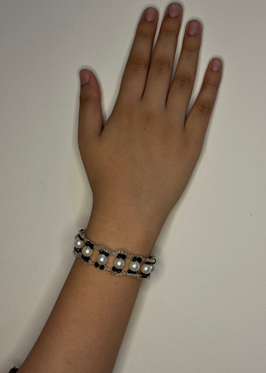 Hand wearing a bracelet on a plain background